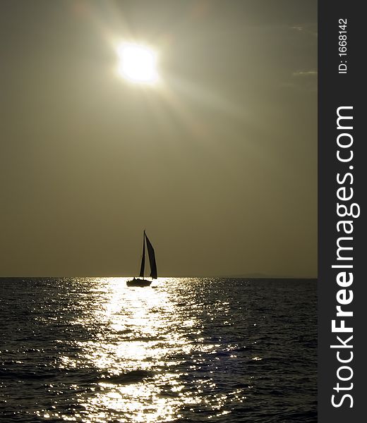 Sailing yacht in a light wind travelling against the golden afternoon sun. Sailing yacht in a light wind travelling against the golden afternoon sun