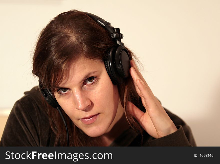 A young female dj is listening to a tune over her headphones.