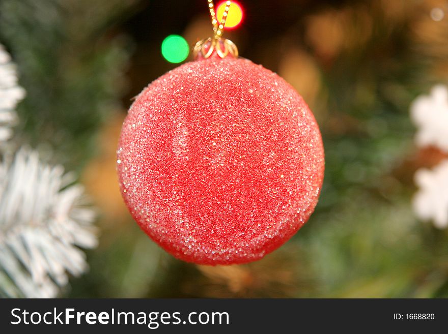 Red bright christmas decoration ball with tree and other objects behind