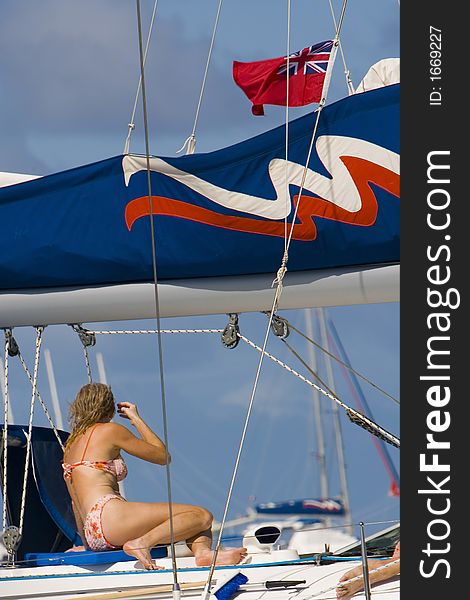 Bikini clad woman catching some rays on a sailboat. Bikini clad woman catching some rays on a sailboat.