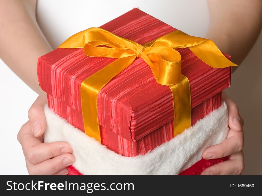 Girl hand holding a christmas present in red hat. Girl hand holding a christmas present in red hat