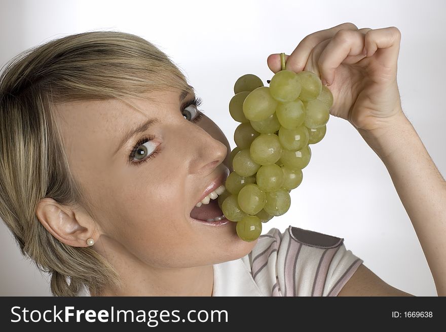 Young woman eating green grapes close up
