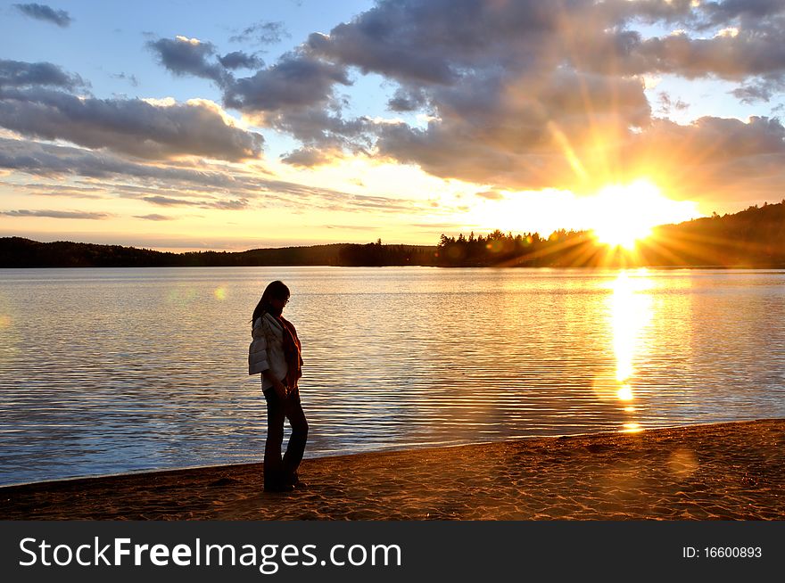 A beatiful girl was walking on the beach in the sunset. The lake of Two Rivers is a quite famous lake in Algonquin, Ontario, Canada. A beatiful girl was walking on the beach in the sunset. The lake of Two Rivers is a quite famous lake in Algonquin, Ontario, Canada