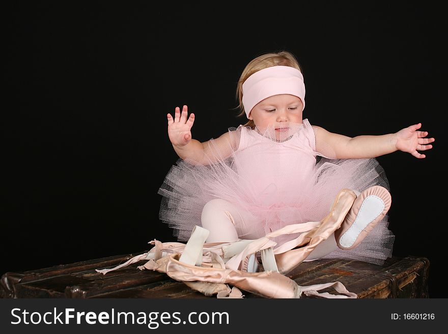 Baby ballerina sitting on an antique trunk