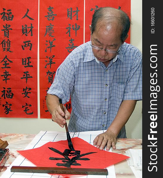 Man writing Chinese calligraphy on red paper. Man writing Chinese calligraphy on red paper