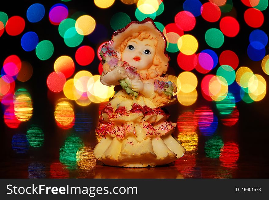 Statuette of a little girl on a background of bright lights.