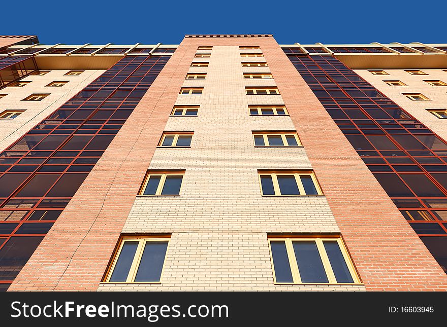 Wall of modern apartment house against a blue sky. Wall of modern apartment house against a blue sky.