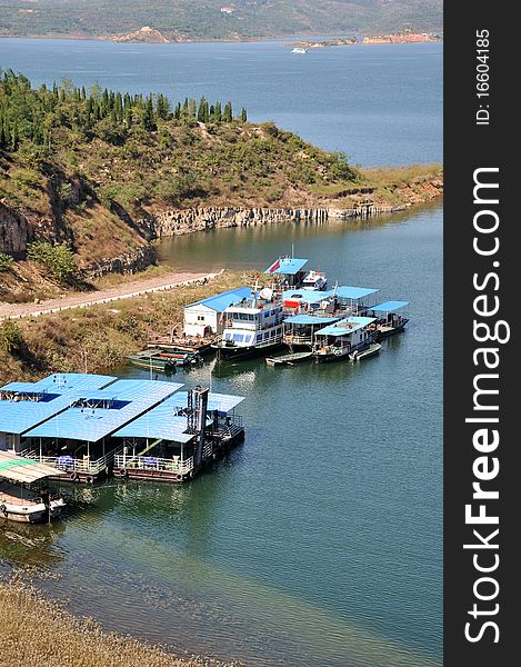 Boat with blue cover are lying beside bank of lake. Boat with blue cover are lying beside bank of lake