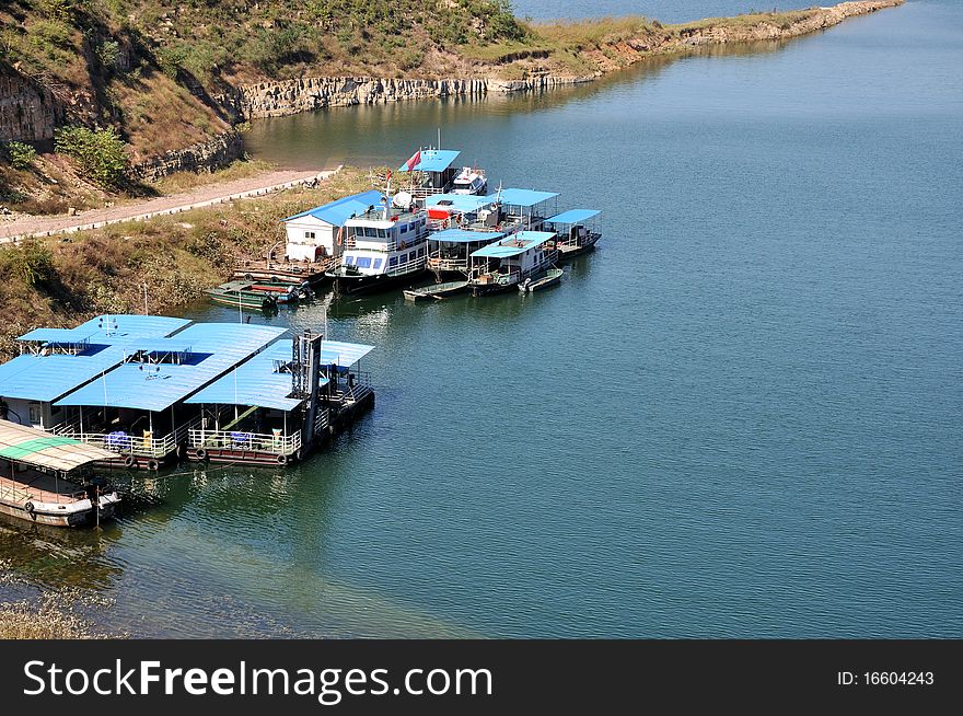 Boat with blue cover are lying beside bank of lake. Boat with blue cover are lying beside bank of lake