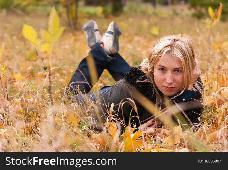 Beautiful young woman lying on autumn leaves with her legs crossed. Beautiful young woman lying on autumn leaves with her legs crossed