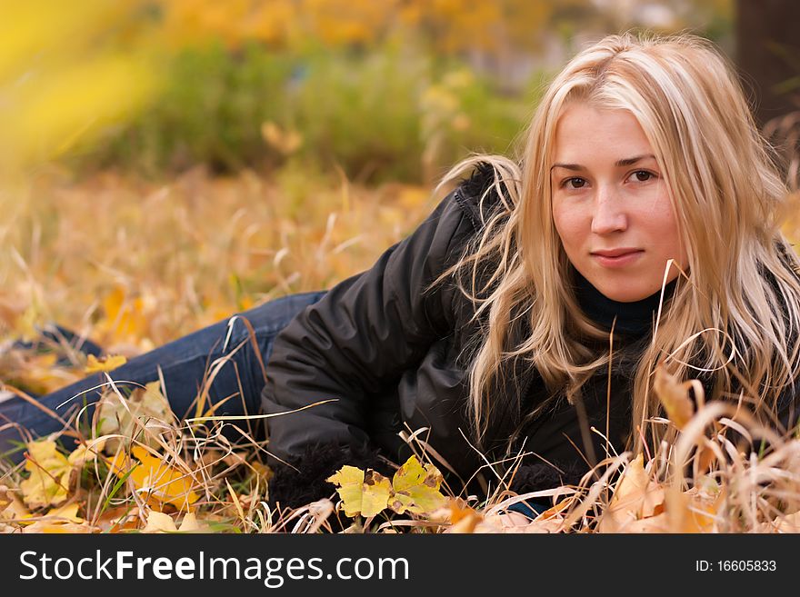 Beautiful young woman lying on autumn leaves