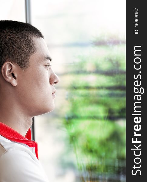 A Chinese young man looking on the window