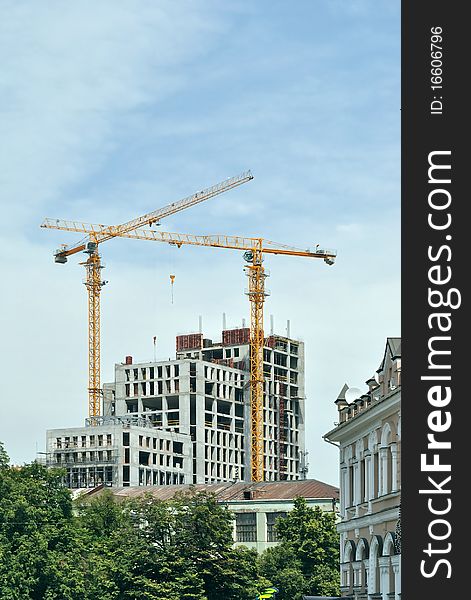 In the historical part of the one of the Ukrainian towns builds modern habitant and office houses. One can see two hoisting cranes against blue sky. In the historical part of the one of the Ukrainian towns builds modern habitant and office houses. One can see two hoisting cranes against blue sky.