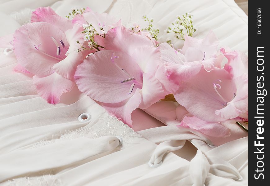 Closeup shot of wedding dress with pink flower on it. Closeup shot of wedding dress with pink flower on it