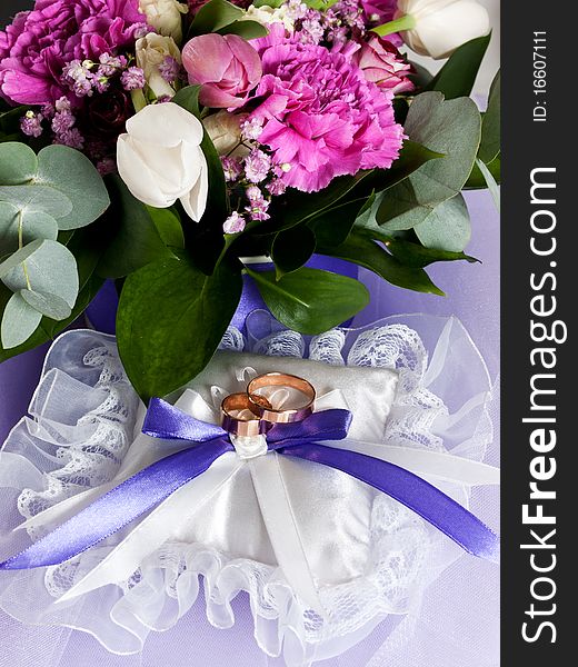 Closeup of wedding rings with a bouquet
