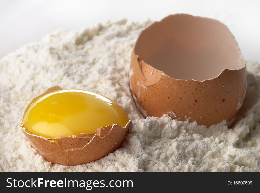 Broken eggshell and yolk in the flour macro shot. Broken eggshell and yolk in the flour macro shot