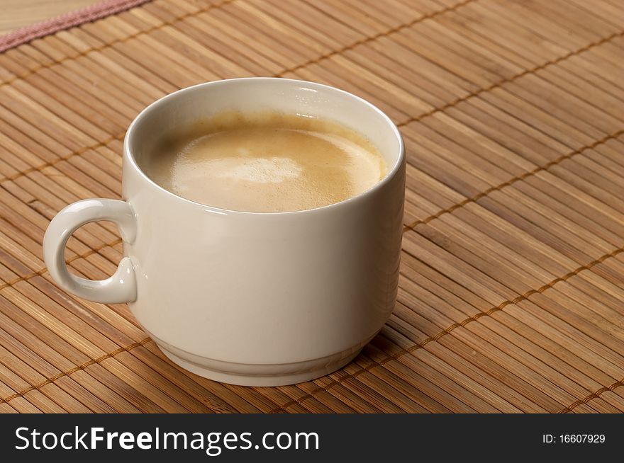 Little white espresso coffee cup on a bamboo mat