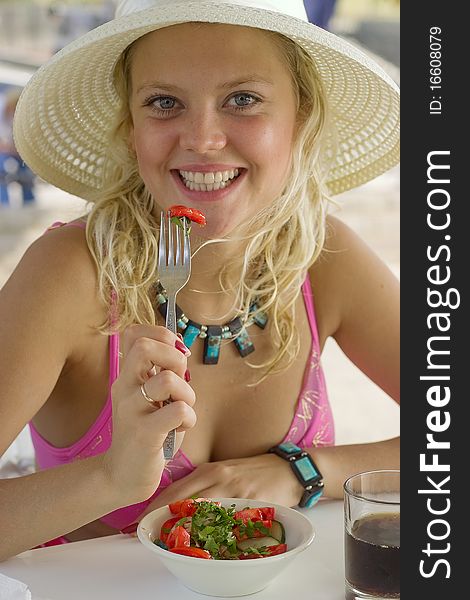 A blonde girl breakfasts in a hat.