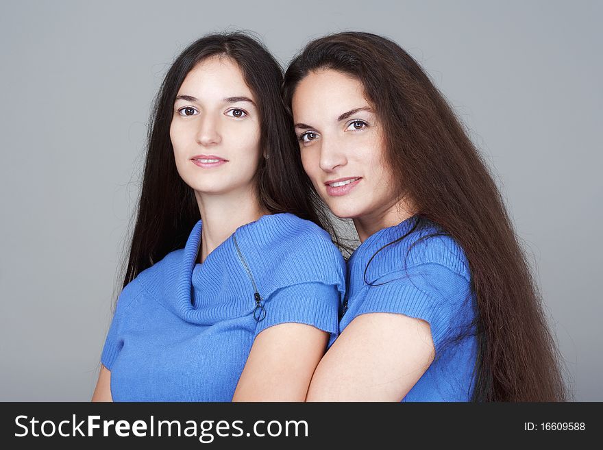 Portrait of two sisters with very long brown hair -isolated on gray