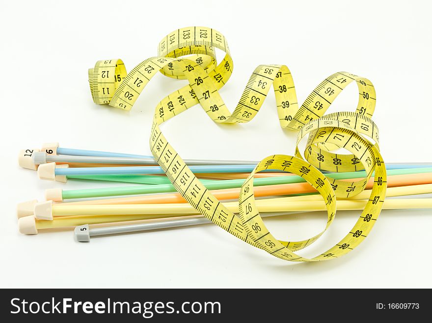 Colorful knitting needles and a yellow measuring tape