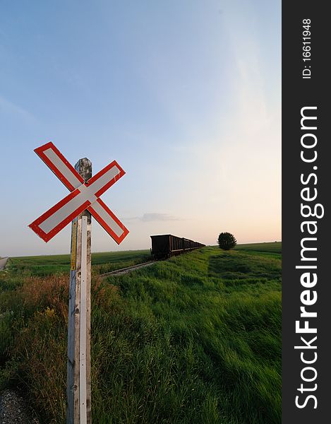 Rural railroad crossing sign in the prairies or grasslands with a blue sky background