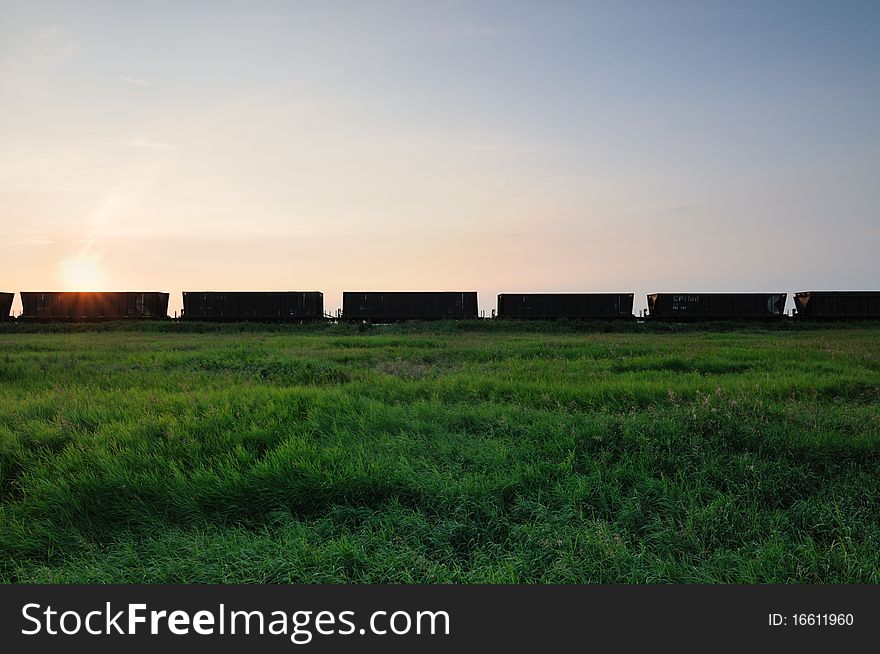 Railroad grain cars in the prairies with blue sky