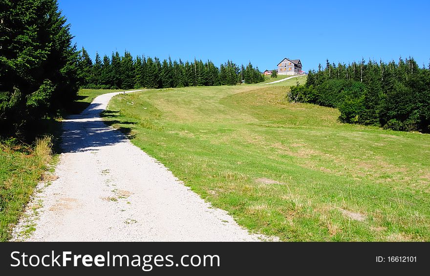 A gravel road on the grassland of the Reisalpe in Lower Austria with the Schutzhaus in the background on the peak. A gravel road on the grassland of the Reisalpe in Lower Austria with the Schutzhaus in the background on the peak