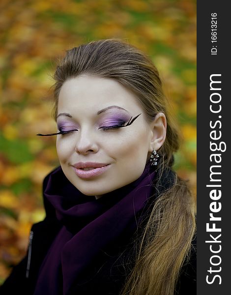 The image of a beautiful girl in a purple dress in the autumn park. The image of a beautiful girl in a purple dress in the autumn park