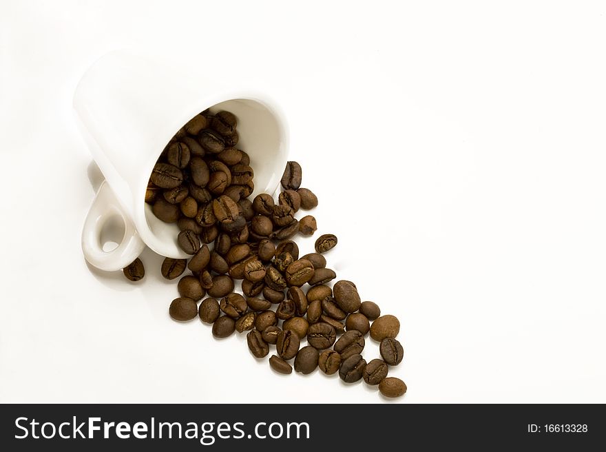 Cup with spilt coffee beans isolated on white
