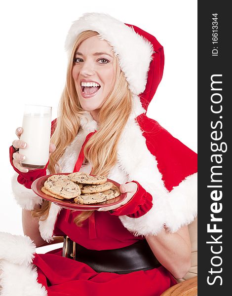 Mrs Santa is holding a plate of cookies and a glass of milk smiling. Mrs Santa is holding a plate of cookies and a glass of milk smiling.