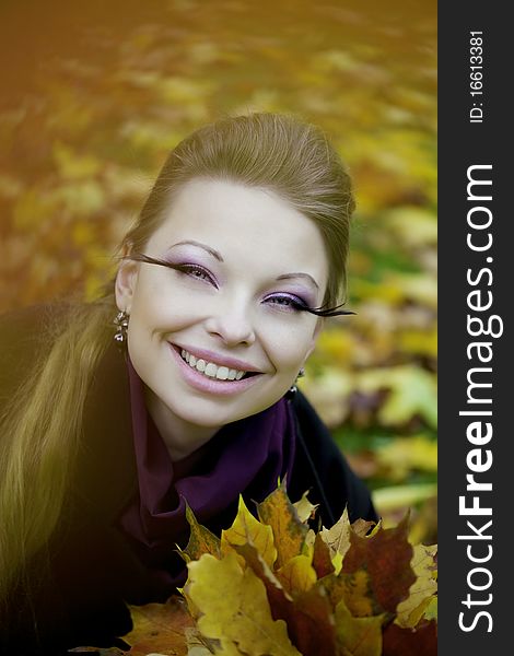 The image of a beautiful girl in a purple dress in the autumn park. The image of a beautiful girl in a purple dress in the autumn park