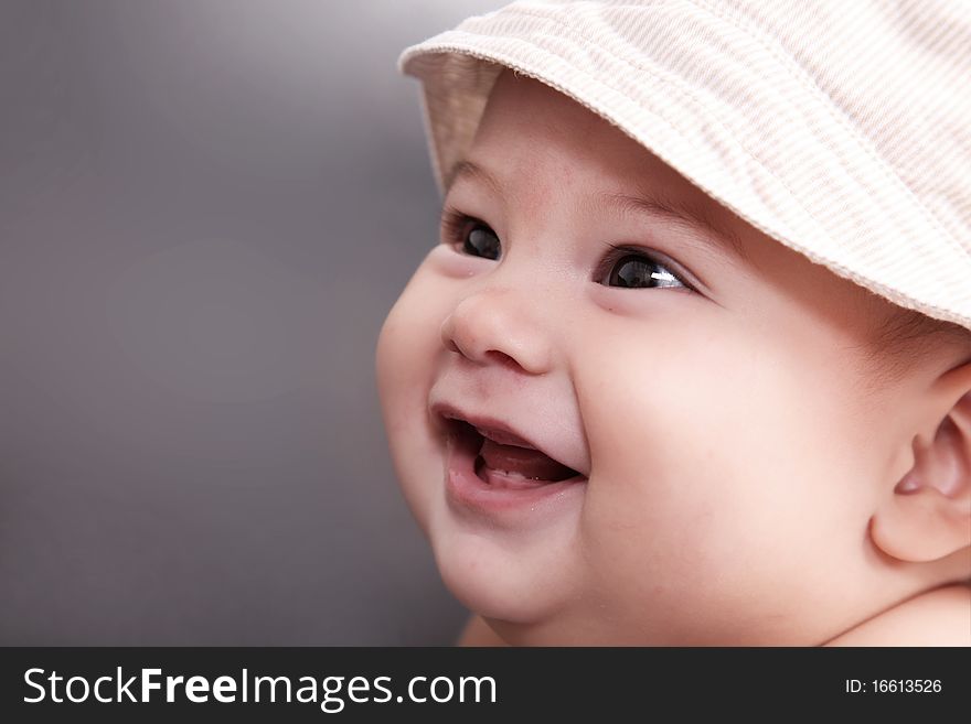 Baby smiling with hat and looking up, gray background. Baby smiling with hat and looking up, gray background