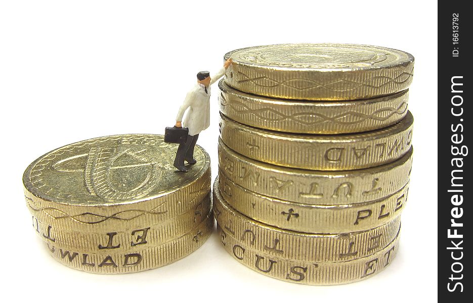 Miniature businessman reaching to the top of a stack of coins. Miniature businessman reaching to the top of a stack of coins