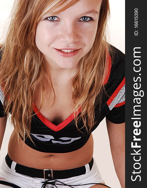 A young teenage soccer girl sitting on the floor in her uniform, in closeup, for a portrait in the studio, over white background. A young teenage soccer girl sitting on the floor in her uniform, in closeup, for a portrait in the studio, over white background.