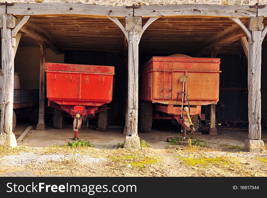 Trailers parked in a barn filled with a corn