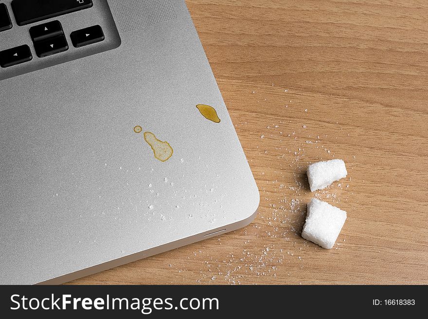 Coffee being dropped on laptop, on a table