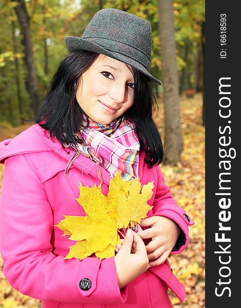 Girl in the hat holds yellow leaves