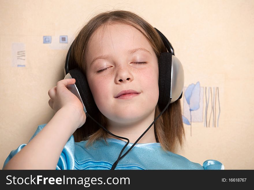 Eight year old girl listening music in headphones indoors