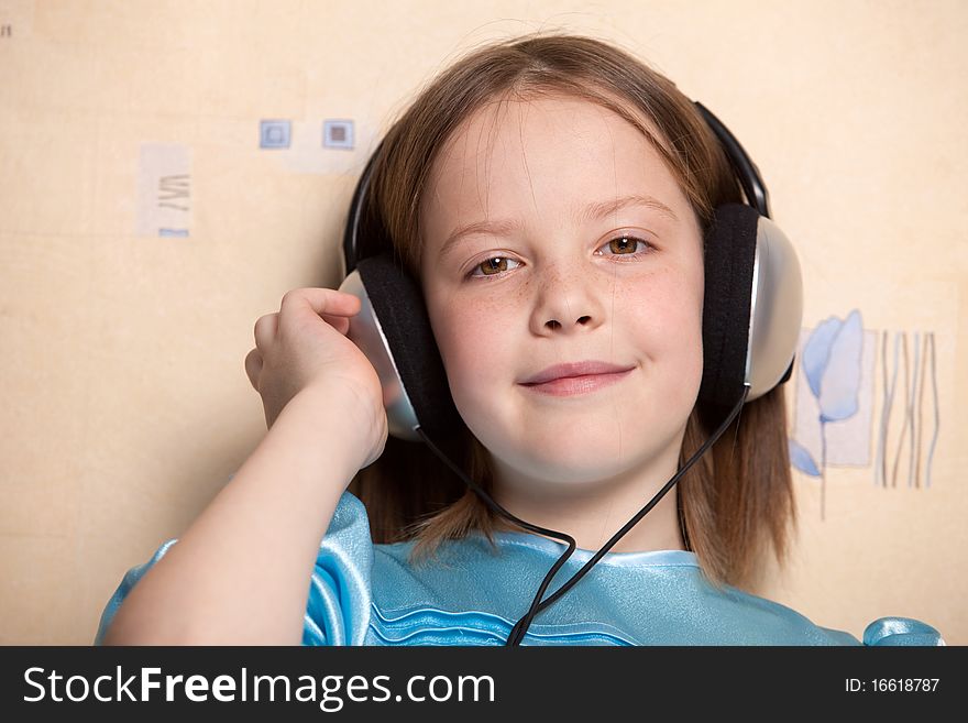 Eight year old girl listening music in headphones indoors