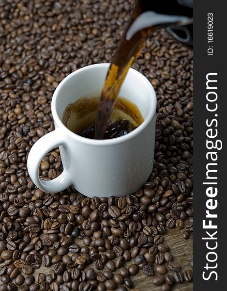 Coffee cup being filled, surrounded by coffee beans. Coffee cup being filled, surrounded by coffee beans