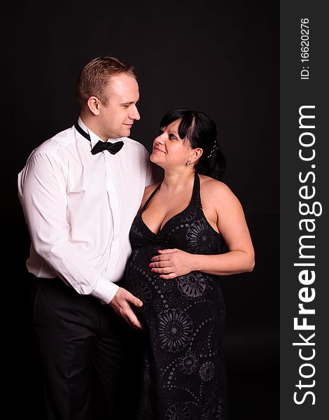 Beautiful young couple expecting their child on black background. Beautiful young couple expecting their child on black background