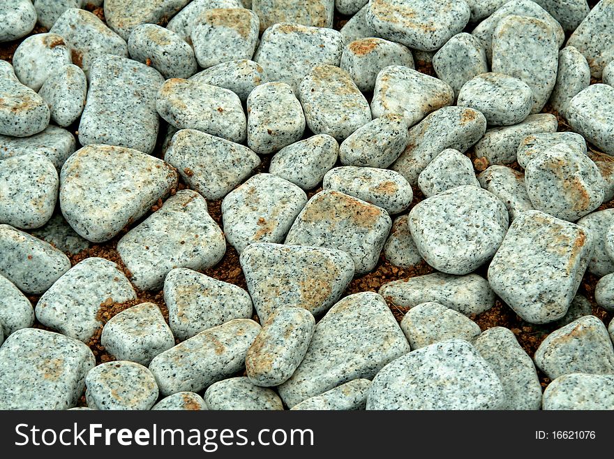 Pavement covered with round-edged, grainy, grey pebbles. Pavement covered with round-edged, grainy, grey pebbles