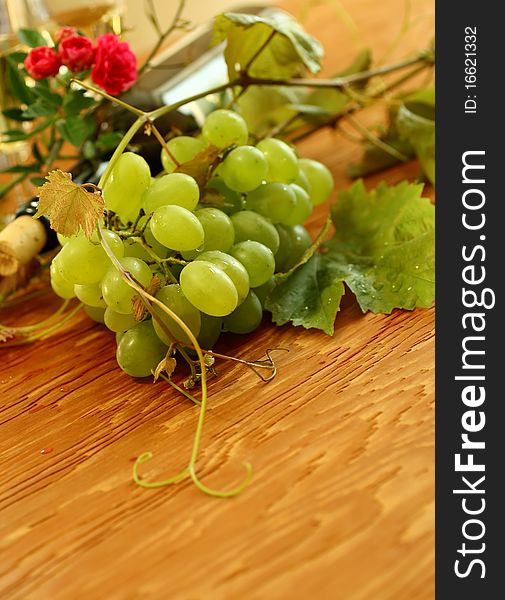 Fresh grapes, vine and vine bottle on wooden background