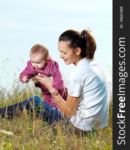 Happy youngl mather with beby outdoor siting on grass