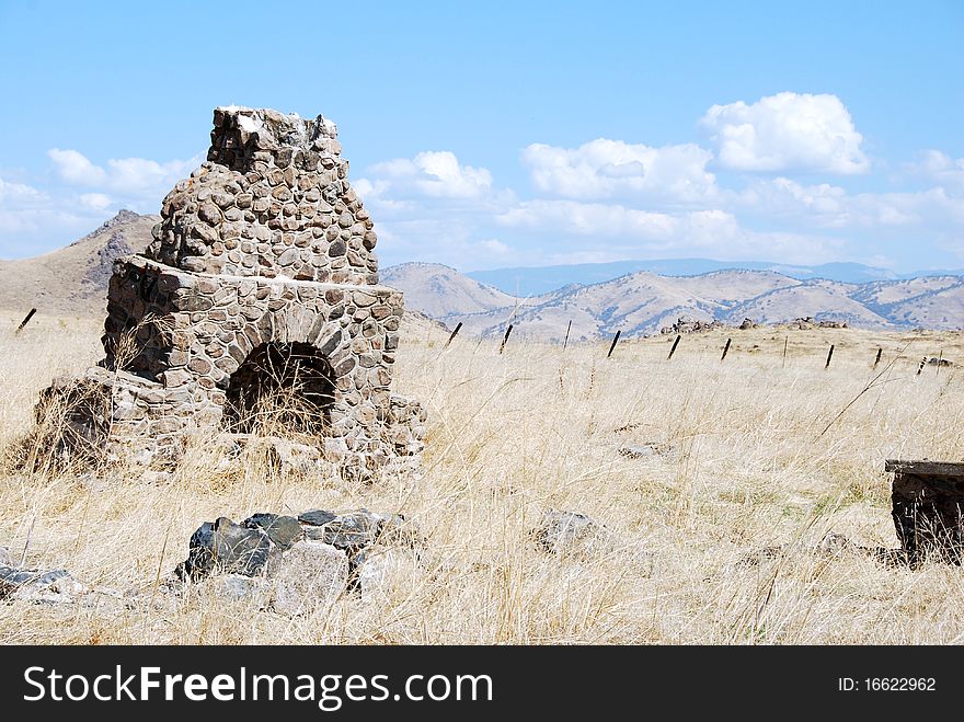 An abandoned chimney stands in the foothills of the Sierra Nevadas with that mountain range in the background. An abandoned chimney stands in the foothills of the Sierra Nevadas with that mountain range in the background.