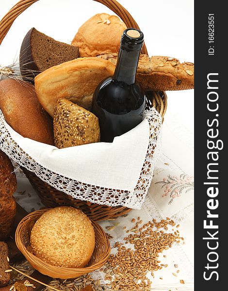 Bread products and wine in basket on white background