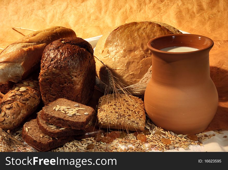 Still-life with  different bread products and jug of milk on brown classical background. Still-life with  different bread products and jug of milk on brown classical background