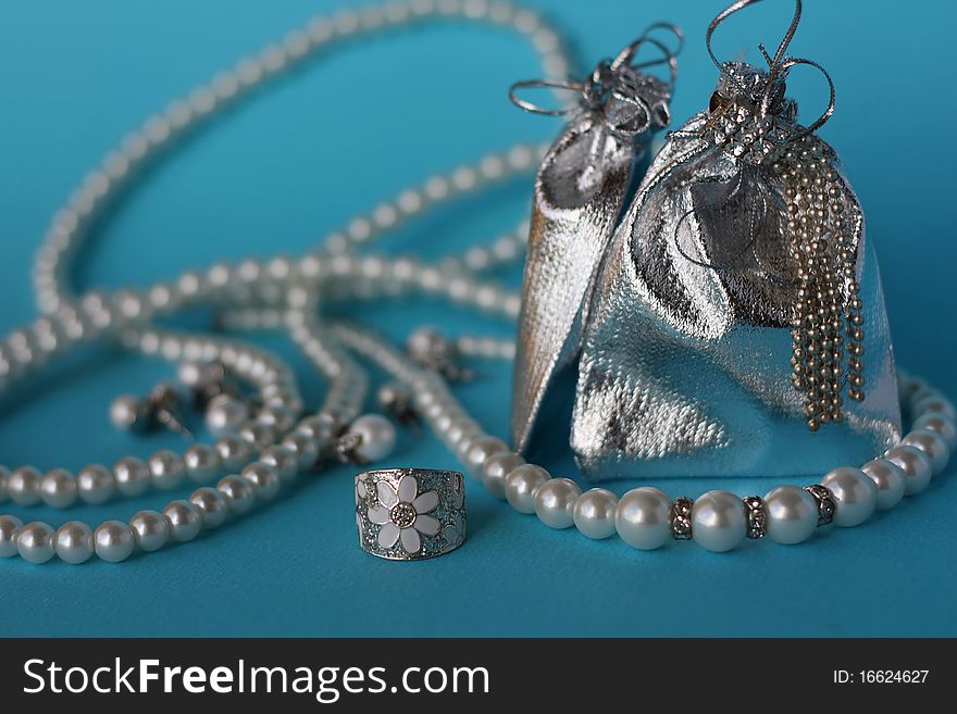 Still Life with pearls and silver jewelry on a blue background