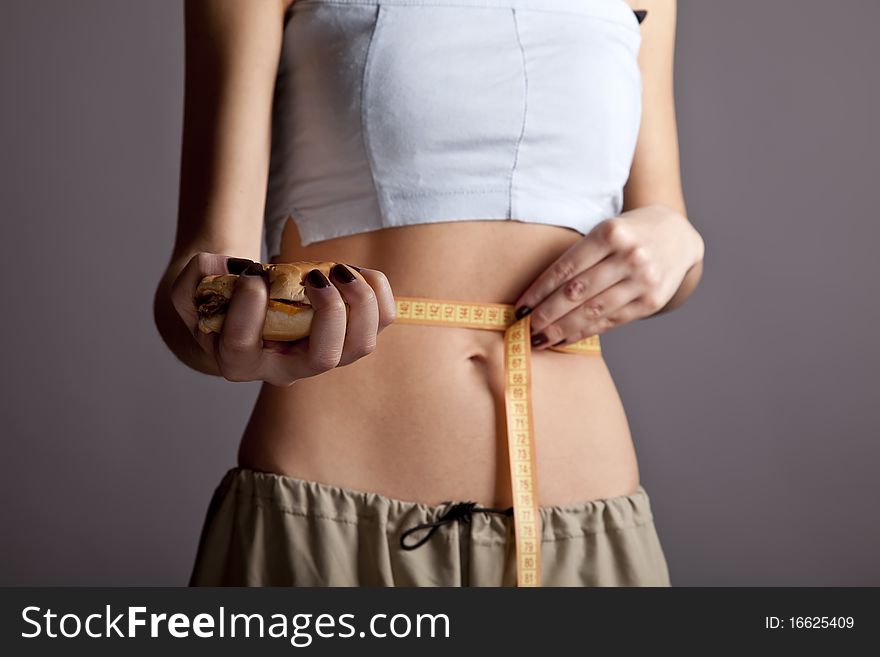 Beautiful and strong women's abs with metre nad burger. Studio shot. Beautiful and strong women's abs with metre nad burger. Studio shot.