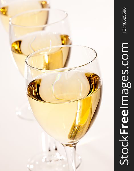 Three glasses with white wine over light bsckground